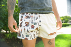 Male model wearing MEROX Traditional Tattoo mesh shorts outdoors, front view