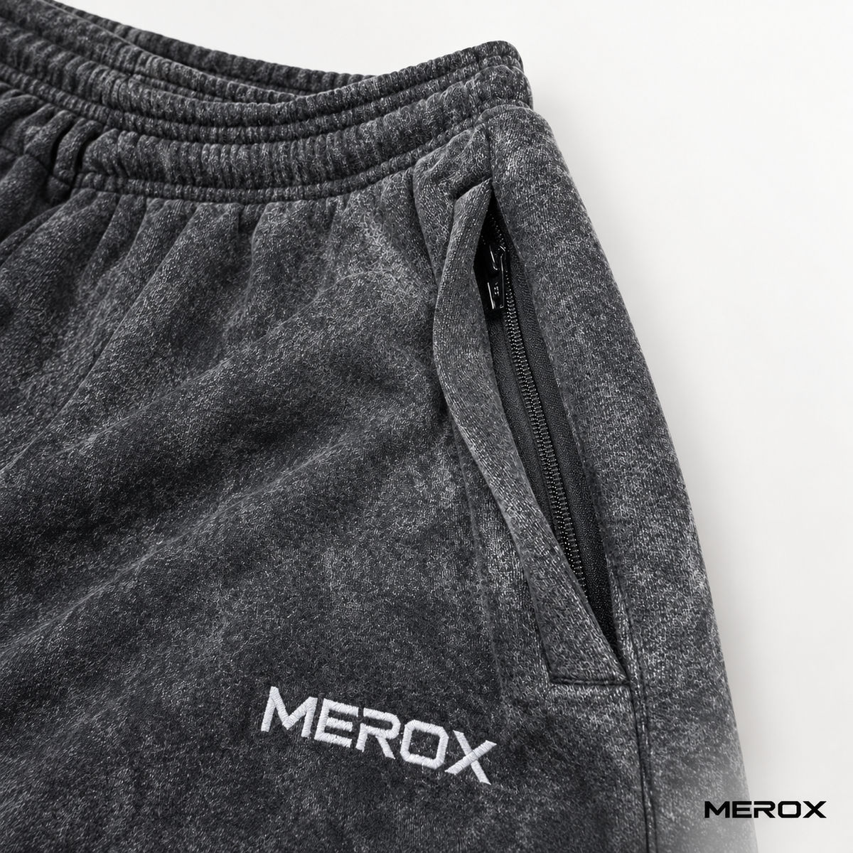 Concealed zipper pocket detail on MEROX black acid wash joggers