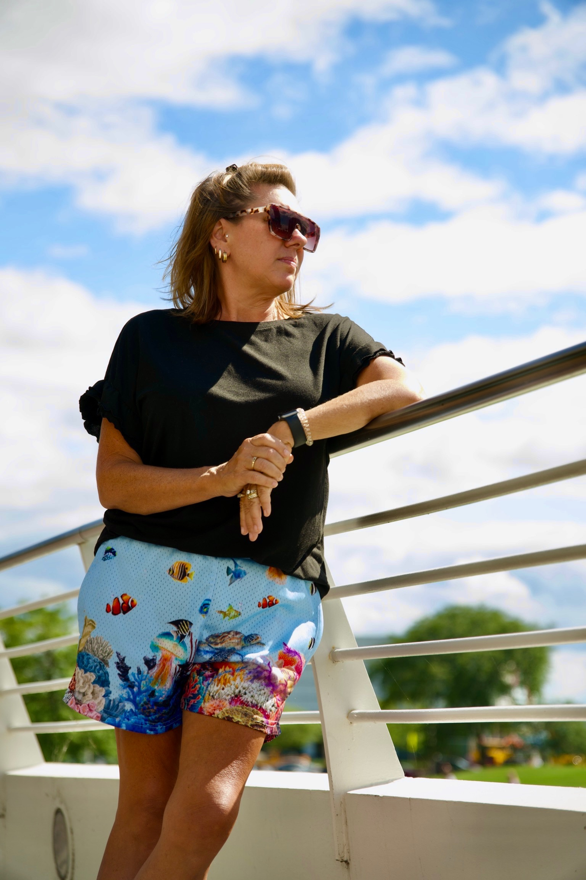 Real adult female model wearing Ocean mesh shorts; localized legacy logo cleanup