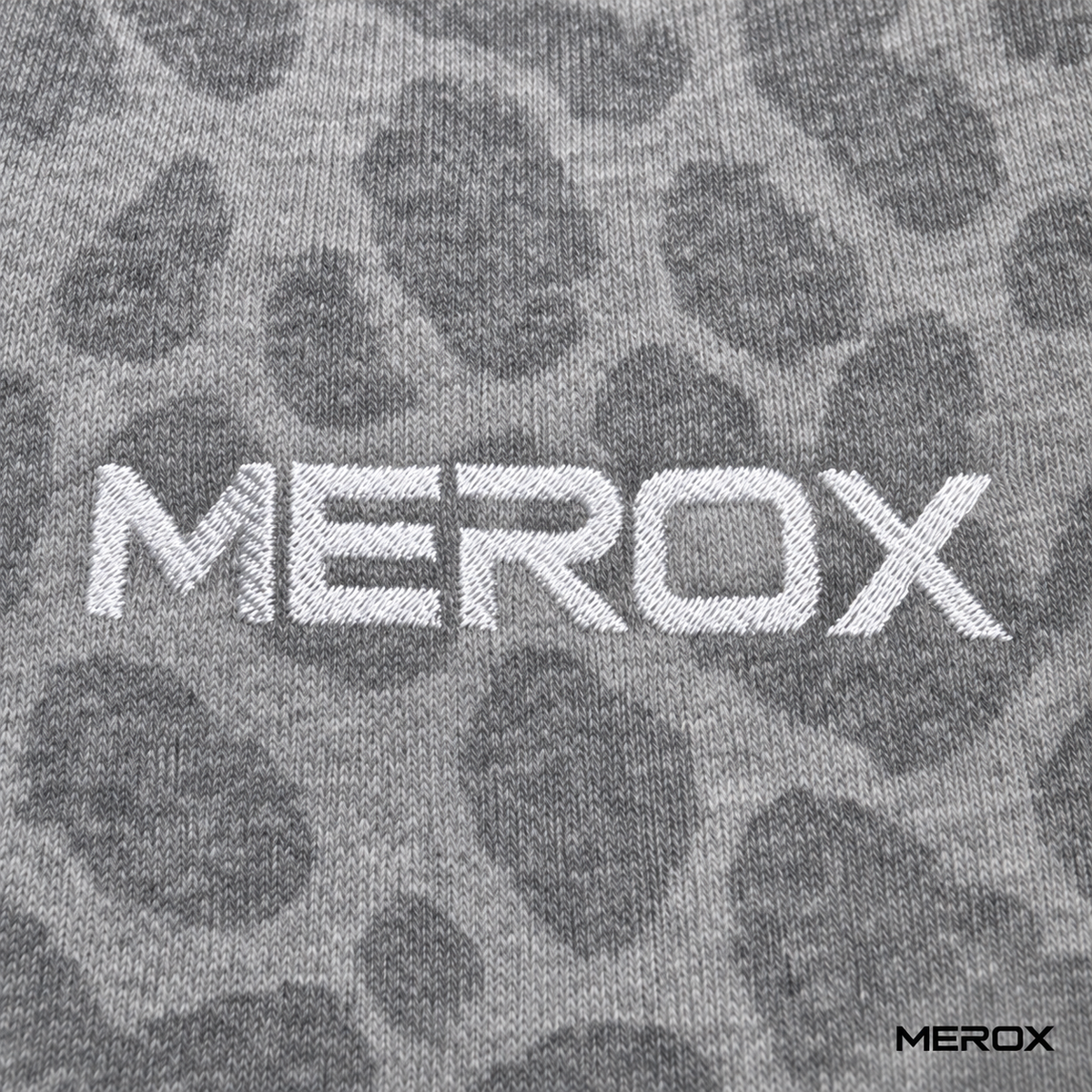 Close-up of white MEROX embroidery and gray cheetah knit texture