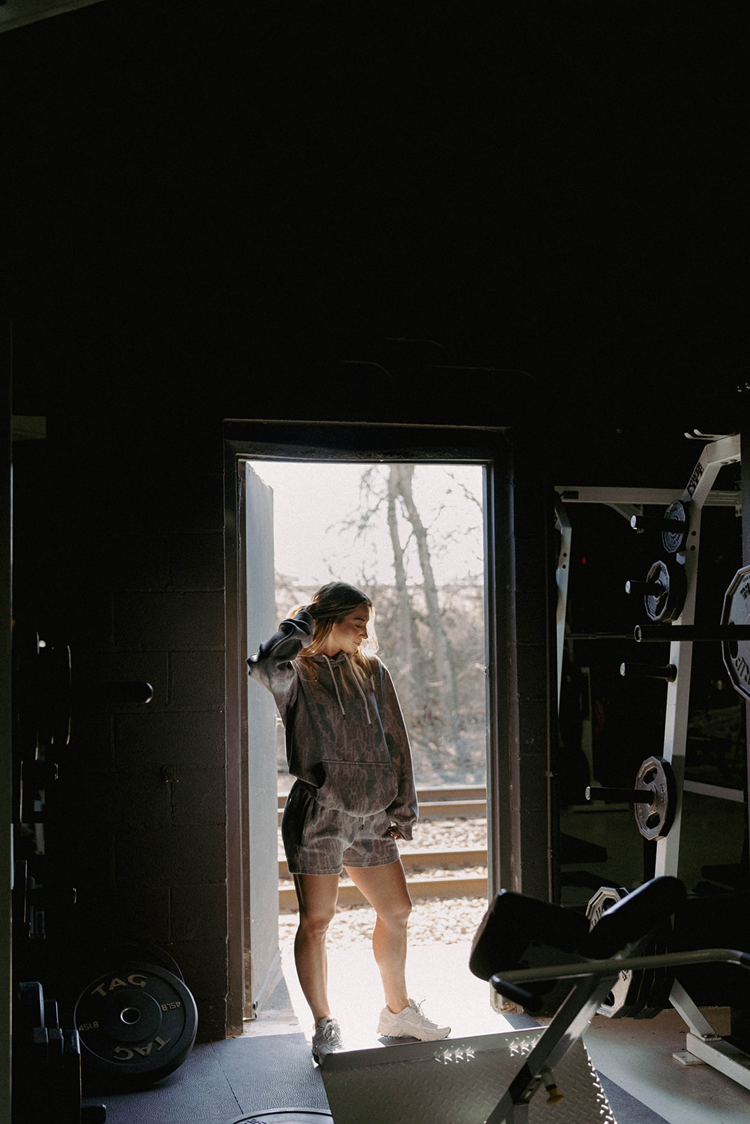 Real model wearing matching Old School Camo cotton shorts and hoodie by gym weights; original photograph with a small legacy logo cleaned up